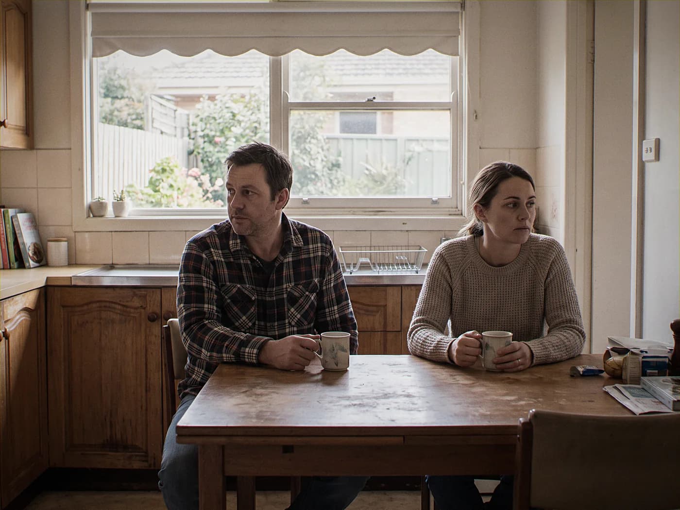 Australian man and woman sitting quietly together at a kitchen table