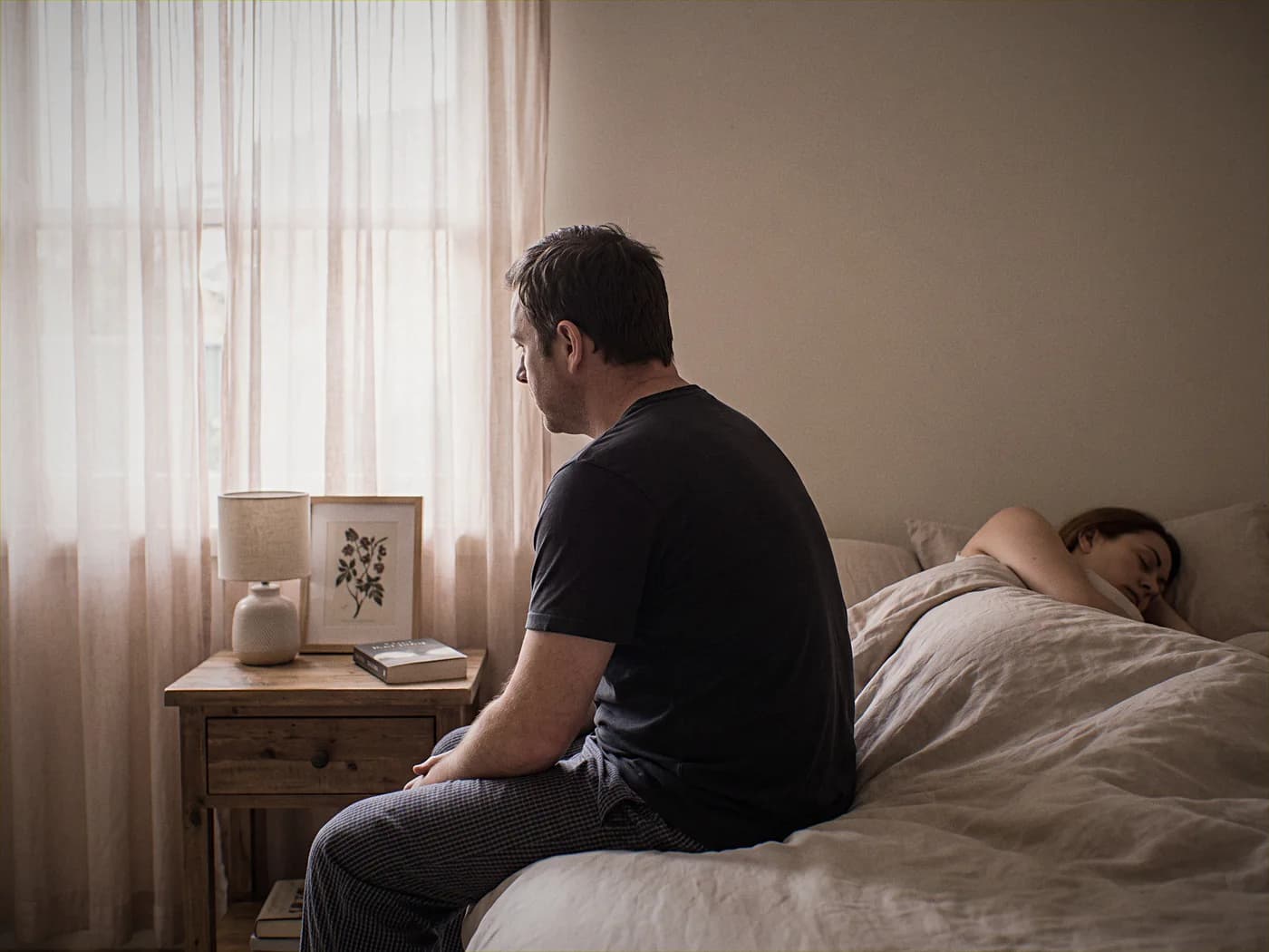 Australian man sitting on the edge of his bed at dawn