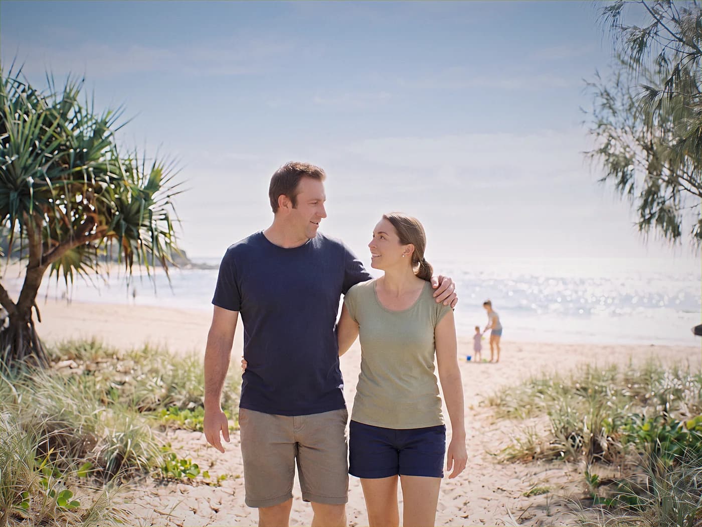 Australian man and woman walking together on a path beside the beach